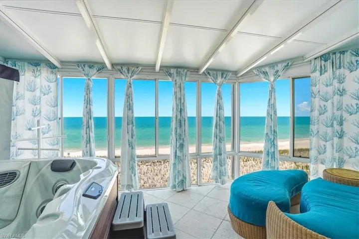 Solarium with full ocean scenery, featuring an in-room spa, tiled flooring, and a beamed ceiling