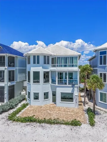 Multi-story coastal residence featuring a white tile roof and light blue exterior