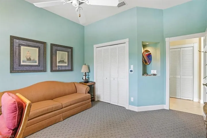 Carpeted room with a vaulted ceiling, white louvered bifold closet doors, and recessed wall niche with lighting