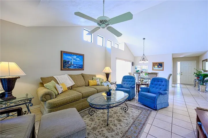 Living room with ceilingchandelier, light tile patterned flooring, and high vaulted ceiling