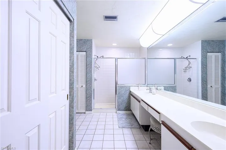 Bathroom featuring tile patterned flooring, vanity, tiled shower, and tile walls