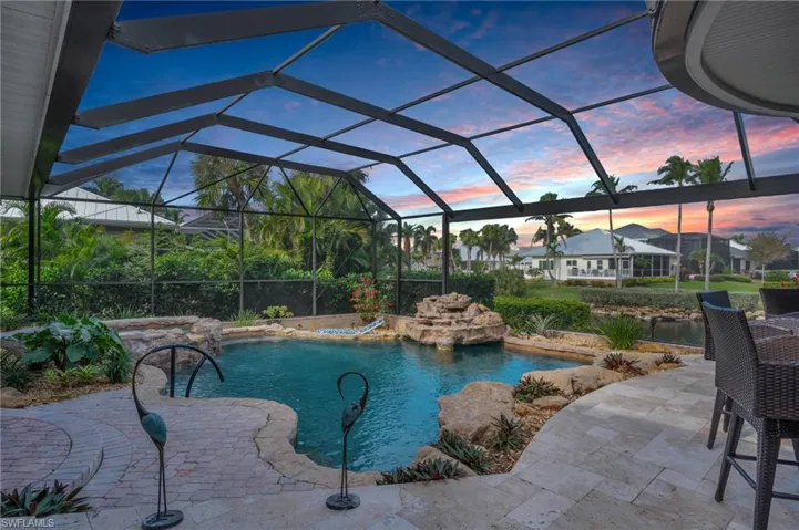 Pool at dusk featuring pool water feature, a patio area, and a lanai