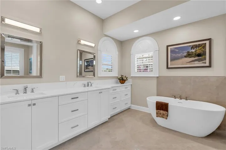 Bathroom featuring tile patterned flooring, vanity, and a bath