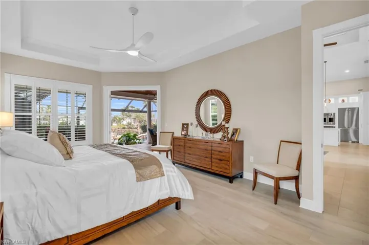 Bedroom with stainless steel fridge, a tray ceiling, and ceiling fan