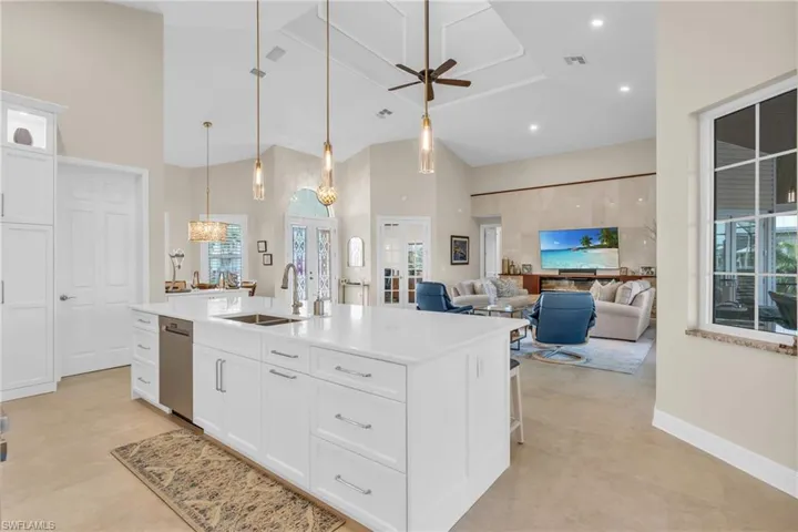 Kitchen with an island with sink, white cabinetry, hanging light fixtures, and sink