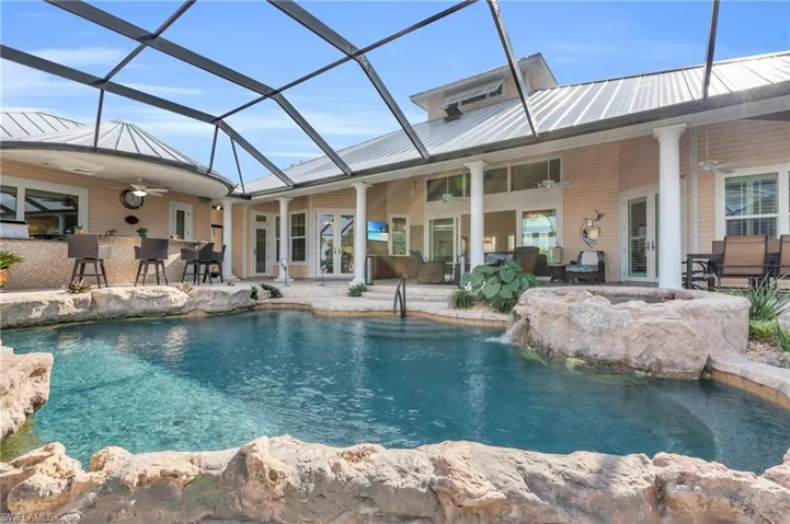 View of swimming pool with ceiling fan, a lanai, pool water feature, a bar, and a patio