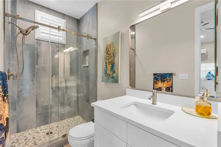 Bathroom with plenty of natural light, vanity, a shower with shower door, and toilet