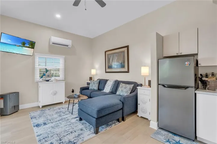 Living room featuring a wall mounted AC, ceiling fan, and light hardwood / wood-style flooring