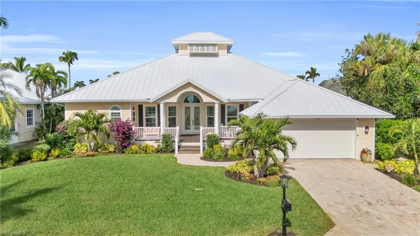 View of front of property featuring a front yard, french doors, a garage, and covered porch