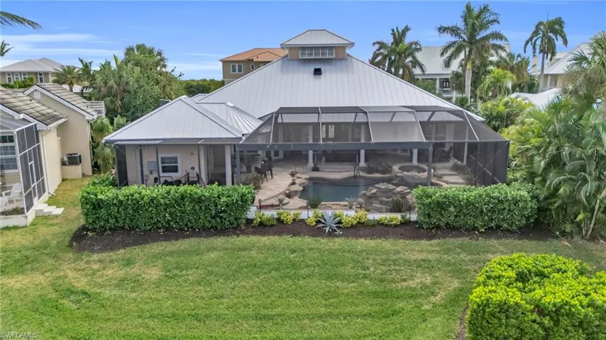 Back of house with a yard and a lanai