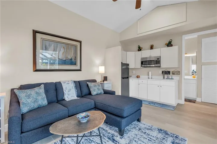 Living room featuring high vaulted ceiling, light hardwood / wood-style flooring, and ceiling fan