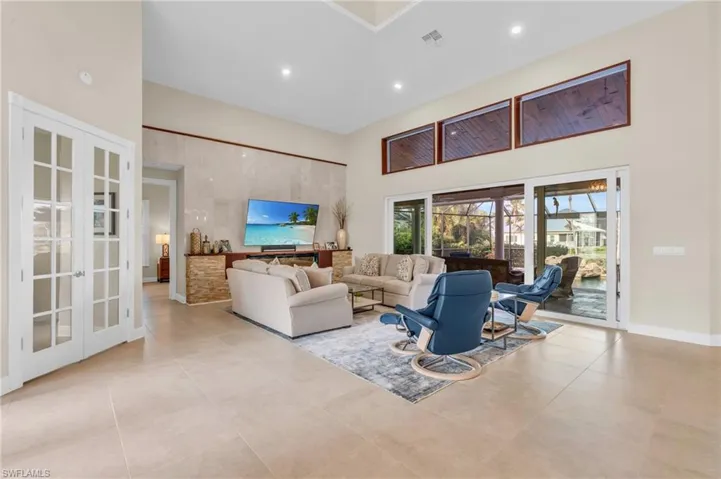 Tiled living room featuring a high ceiling and french doors