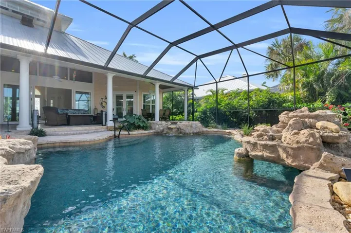 View of pool featuring glass enclosure, ceiling fan, and a patio area
