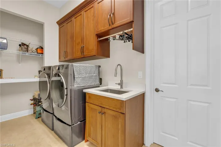 Washroom with washer and dryer, light tile patterned flooring, cabinets, and sink