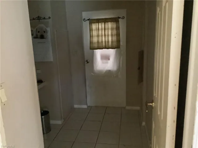 Corridor featuring light tile patterned flooring and baseboards