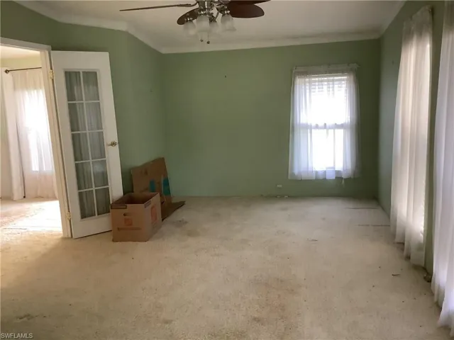 Carpeted empty room featuring crown molding and a ceiling fan