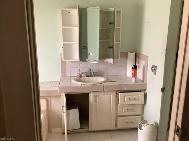 Bathroom featuring decorative backsplash, tile patterned floors, and vanity