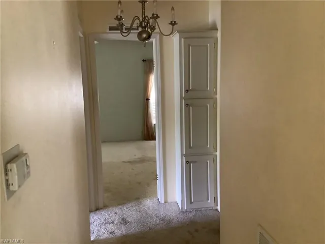Hallway featuring a chandelier and carpet flooring