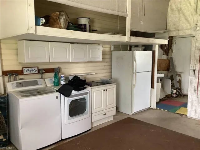 Kitchen with separate washer and dryer, freestanding refrigerator, white cabinetry, and unfinished concrete floors