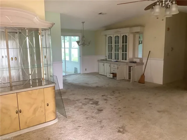 Unfurnished dining area with carpet floors, lofted ceiling, ceiling fan, and a chandelier