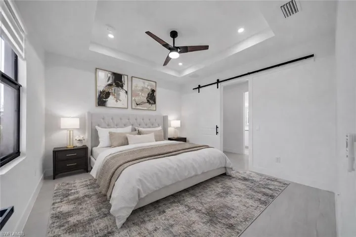 Bedroom with a barn door, a ceiling fan, and recessed lighting