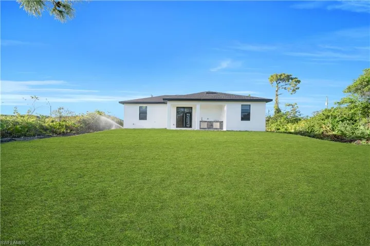 Back of house with stucco siding and a lawn