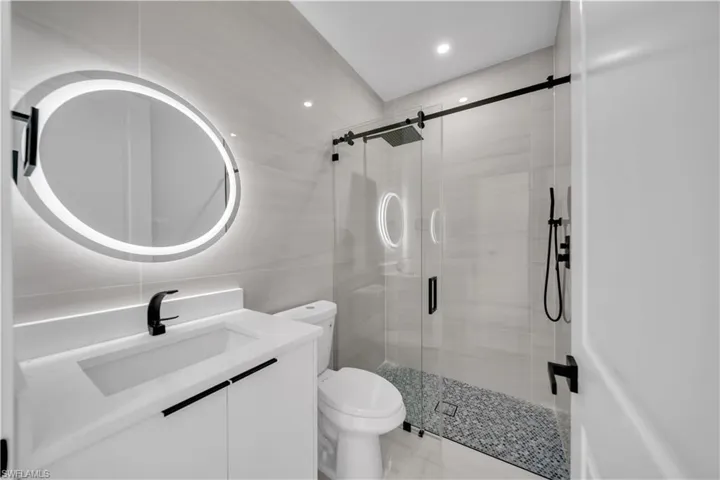 Full bath featuring vanity, a shower stall, tile walls, and recessed lighting