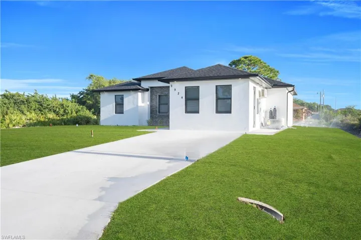 Prairie-style house featuring a front lawn, stucco siding, and concrete driveway