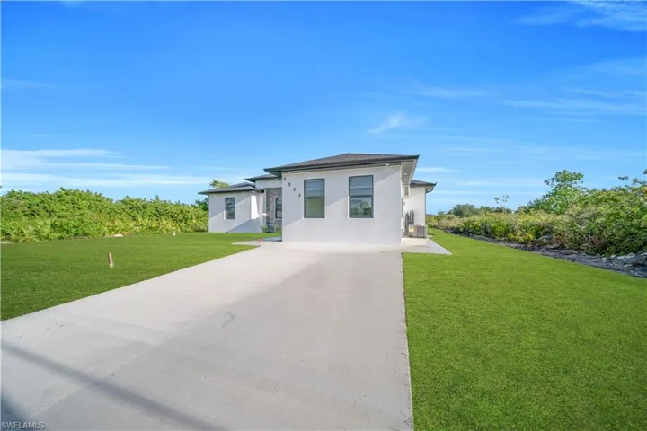 Prairie-style home featuring concrete driveway, stucco siding, and a front lawn