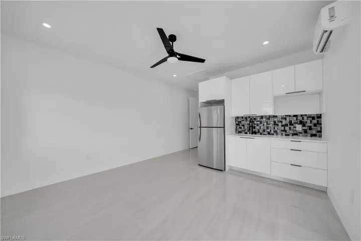 Kitchen featuring white cabinetry, freestanding refrigerator, modern cabinets, light countertops, and recessed lighting