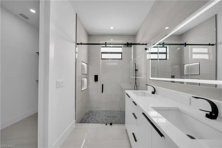 Full bath with double vanity, a stall shower, and recessed lighting