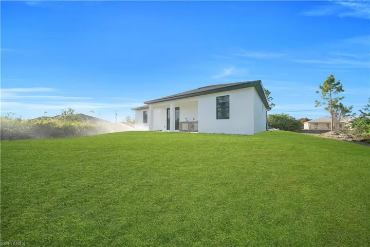 Rear view of property with a yard, stucco siding, and a patio
