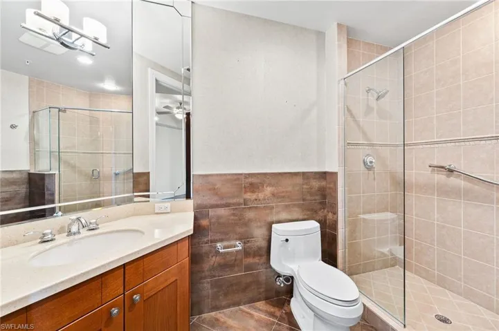 3rd full ensuite bathroom with single vanity, tile walls, walk in shower.