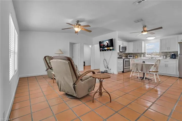 Living room featuring light tile patterned floors, ceiling fan, and visible vents