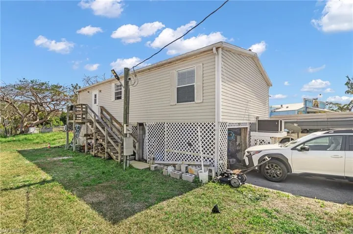 View of property exterior with stairs and a lawn