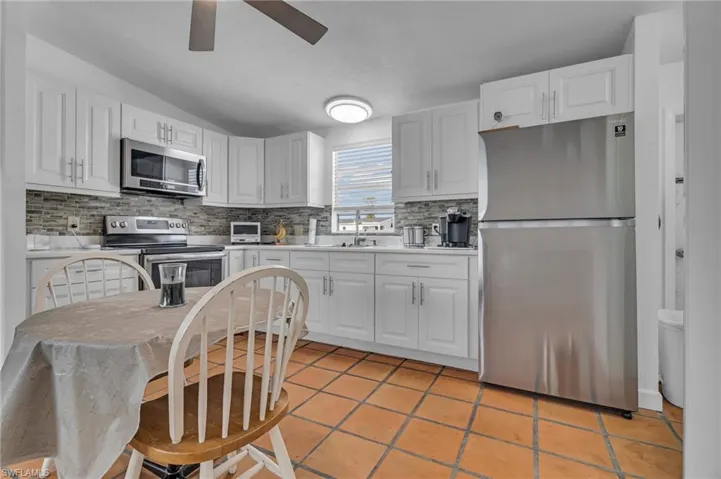 Kitchen with stainless steel appliances, light countertops, and white cabinetry