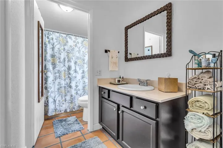 Full bath featuring toilet, curtained shower, vanity, and tile patterned floors