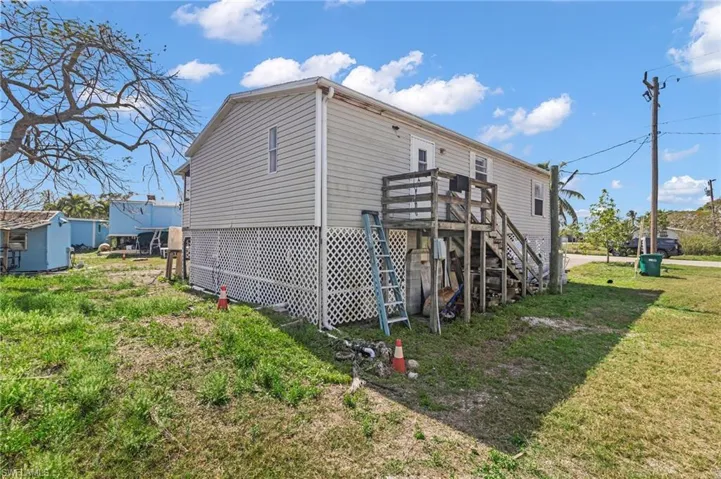 Rear view of house with stairway and a lawn