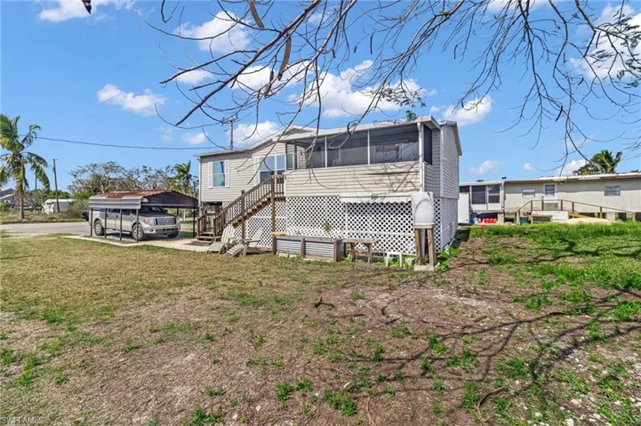 Back of property featuring a sunroom, a yard, and stairs