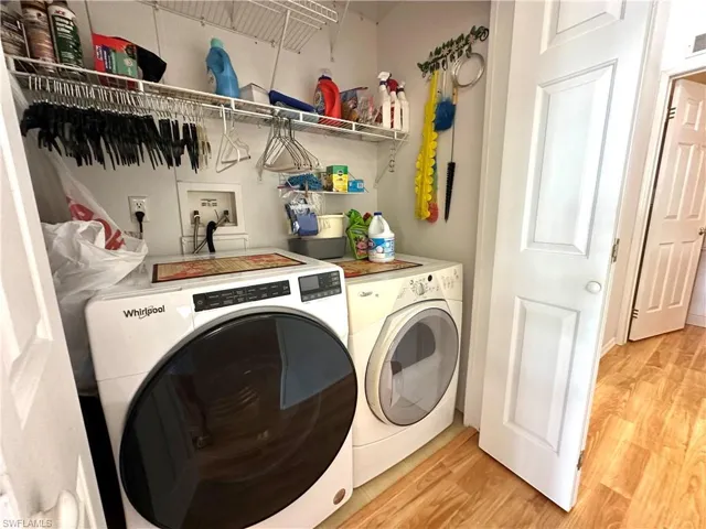 Clothes washing area featuring washing machine and dryer, hookup for a washing machine, and light hardwood / wood-style floors