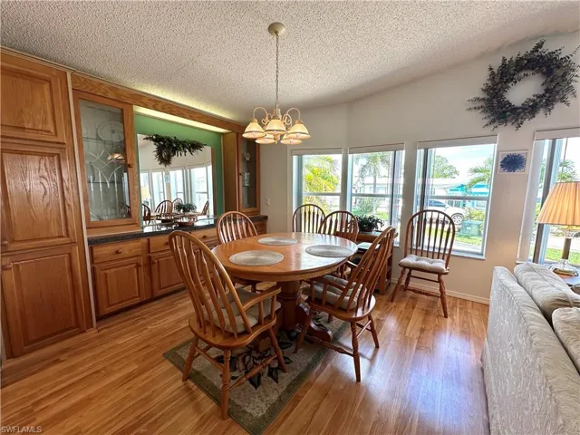 Dining room featuring a notable chandelier, a textured ceiling, and light wood-type flooring