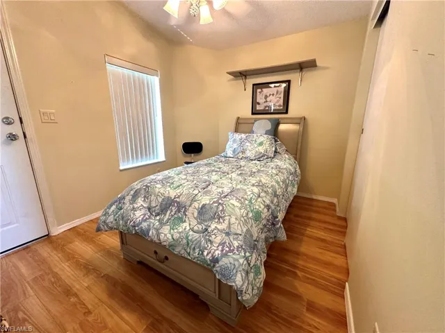 Bedroom with ceiling fan, a textured ceiling, and wood-type flooring