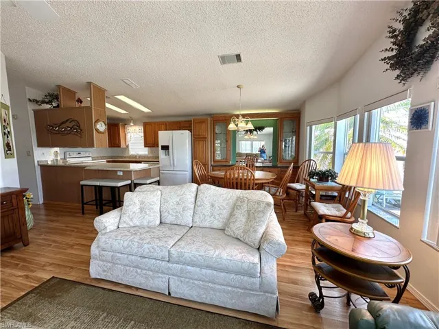 Living room featuring a textured ceiling, light wood-type flooring, and a chandelier