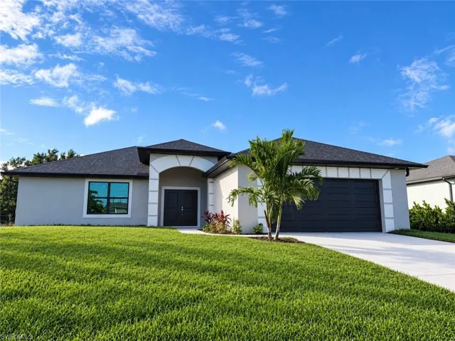 Single-story exterior featuring a high-contrast facade, arched entryway, dark-toned double front doors, an attached two-car garage, and manicured landscaping