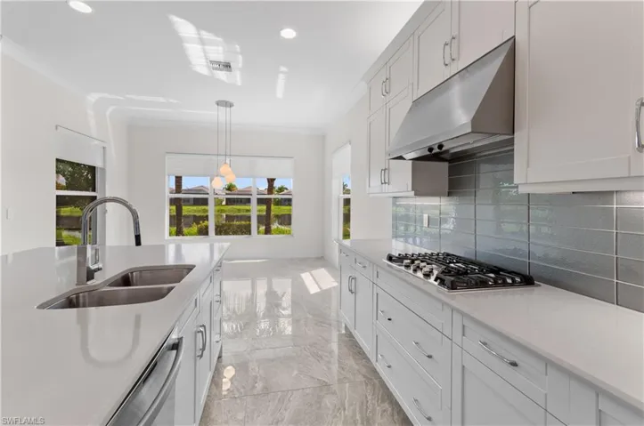 Kitchen featuring appliances with stainless steel finishes, decorative backsplash, white cabinets, crown molding, and sink