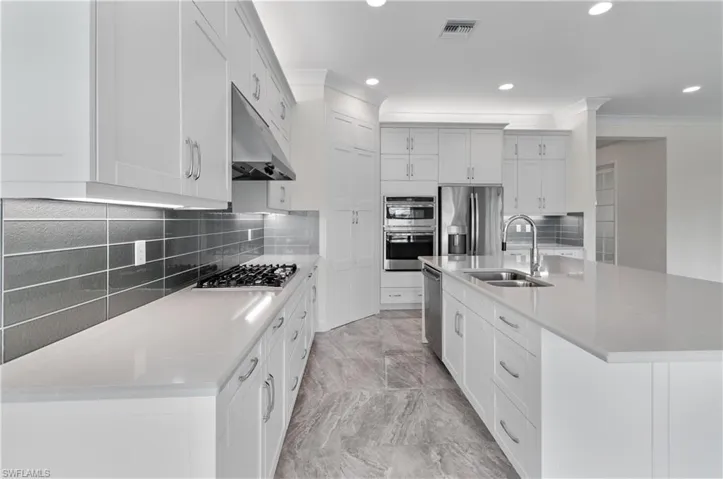Kitchen featuring an island with sink, white cabinetry, and appliances with stainless steel finishes