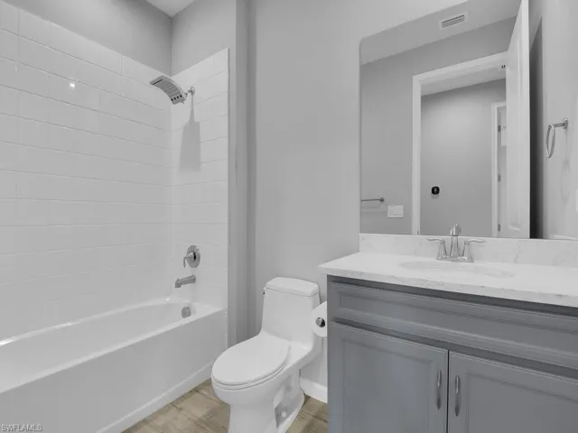 Full bathroom featuring toilet, tiled shower / bath combo, hardwood / wood-style flooring, and vanity