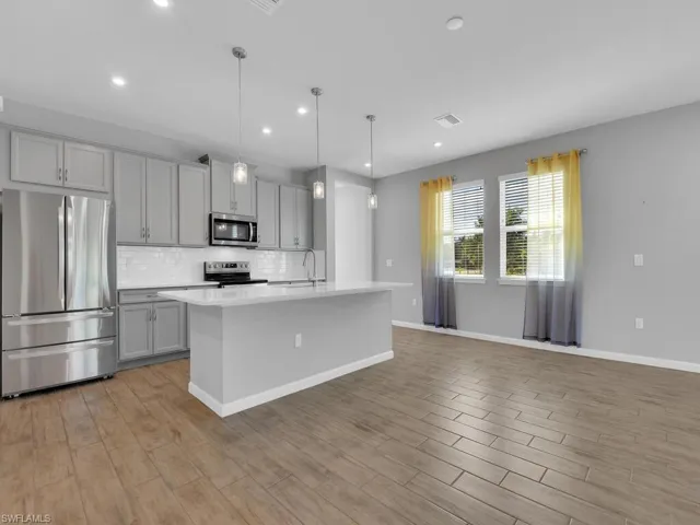 Kitchen featuring gray cabinets, stainless steel appliances, hanging light fixtures, and tile flooring