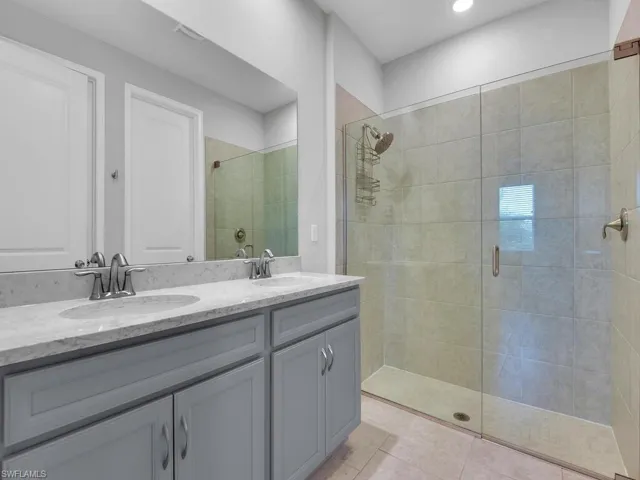 Bathroom featuring vanity, a shower with shower door, and tile patterned flooring