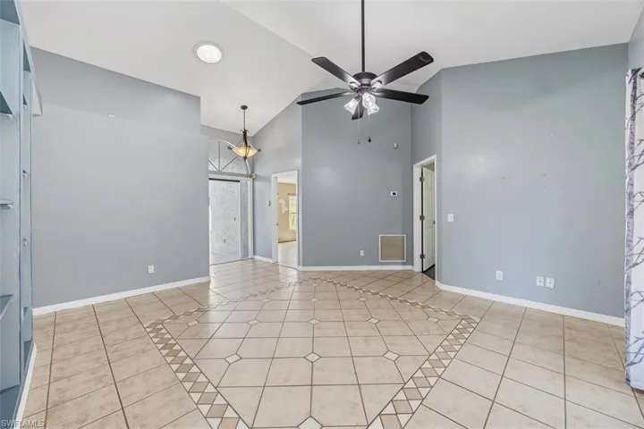 Unfurnished room with high vaulted ceiling, light tile patterned flooring, ceiling fan, and inlaid floor details